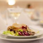 Plate of gourmet salad with bread on a elegantly set restaurant table, perfect for upscale dining experiences.